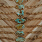 Gold chains with turquoise stone pendants on a wooden surface