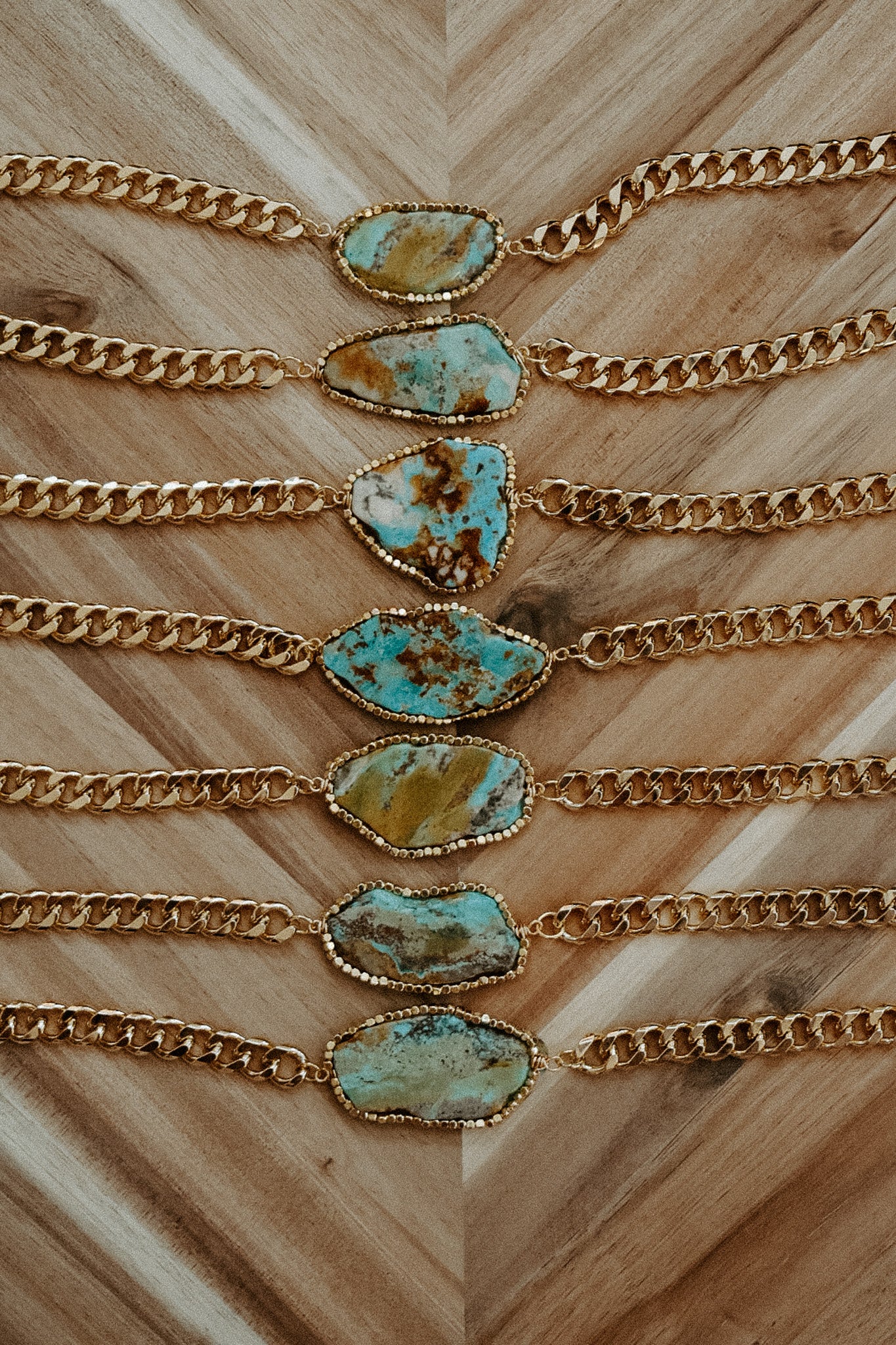 Gold chains with turquoise stone pendants on a wooden surface