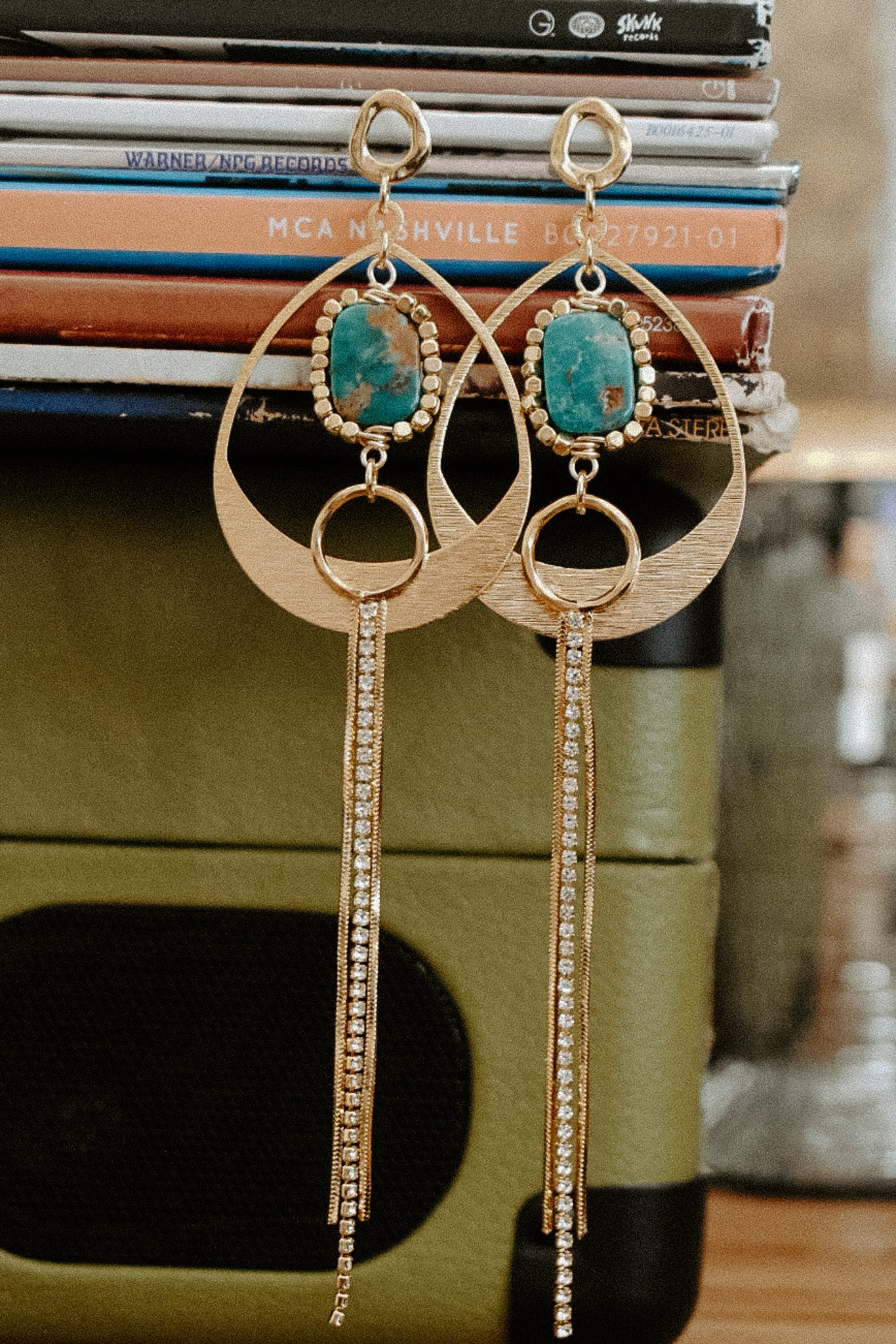 Gold earrings with turquoise stones on a stack of books